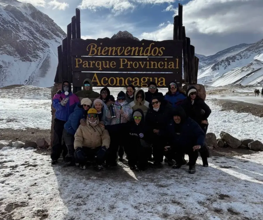Integrantes de AliPro con remeras de la marca, frente a la cordillera y un lago