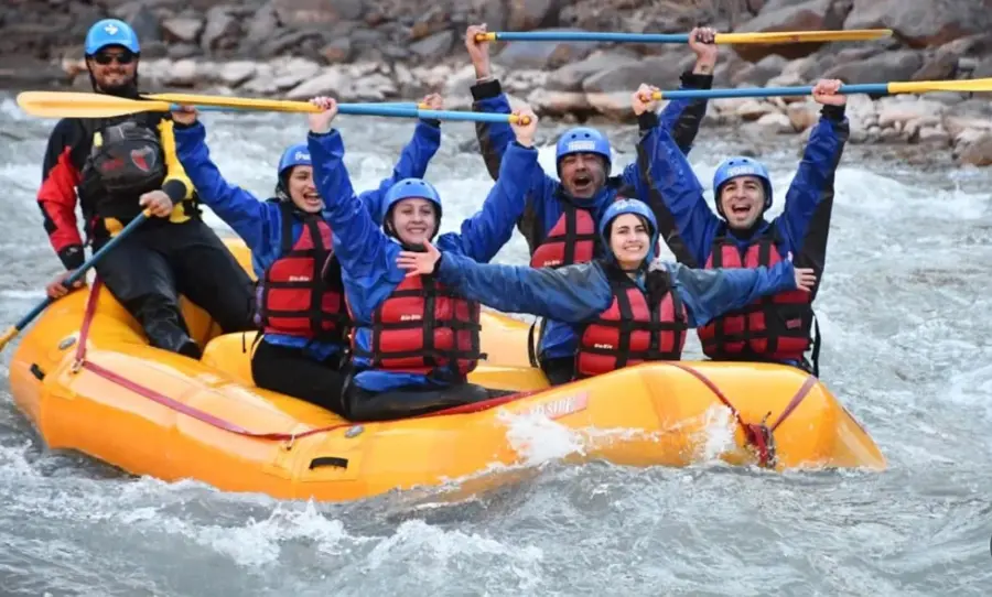 Grupo de la comunidad haciendo rafting en un río de montaña