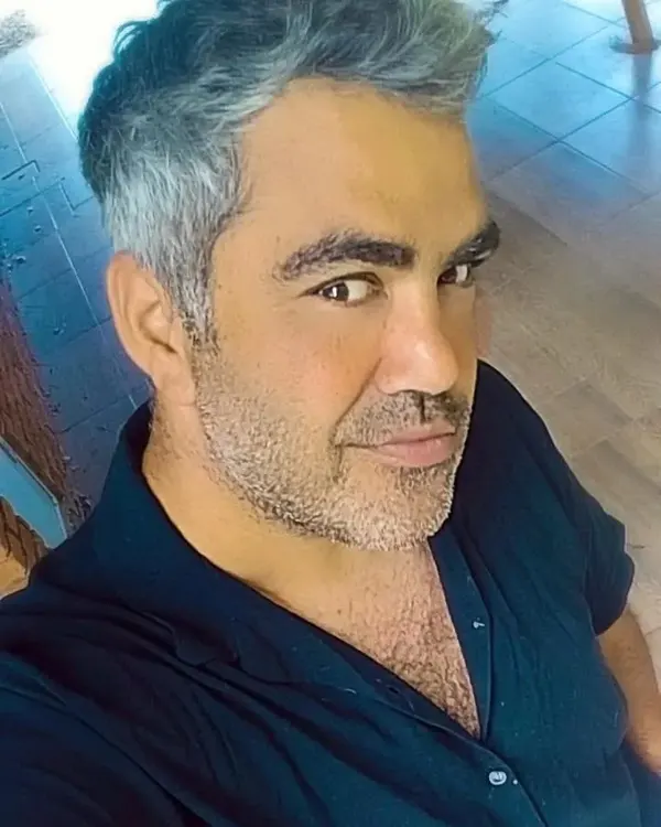 Retrato de Pachi Silva sonriendo, con camisa azul oscuro